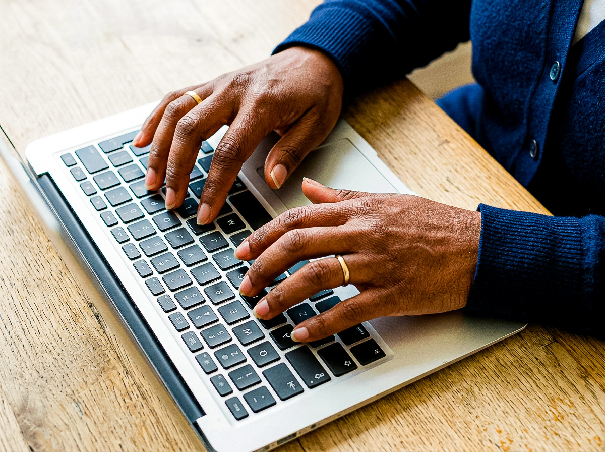 Close-up of a pair of hands typing on a laptop keyboard